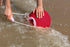 Child scooping up sea water with red bucket