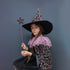 Child in a Halloween costume with a witch hat and colorful star wand against a gray background