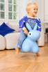 Child riding a blue inflatable bunny toy in a living room.