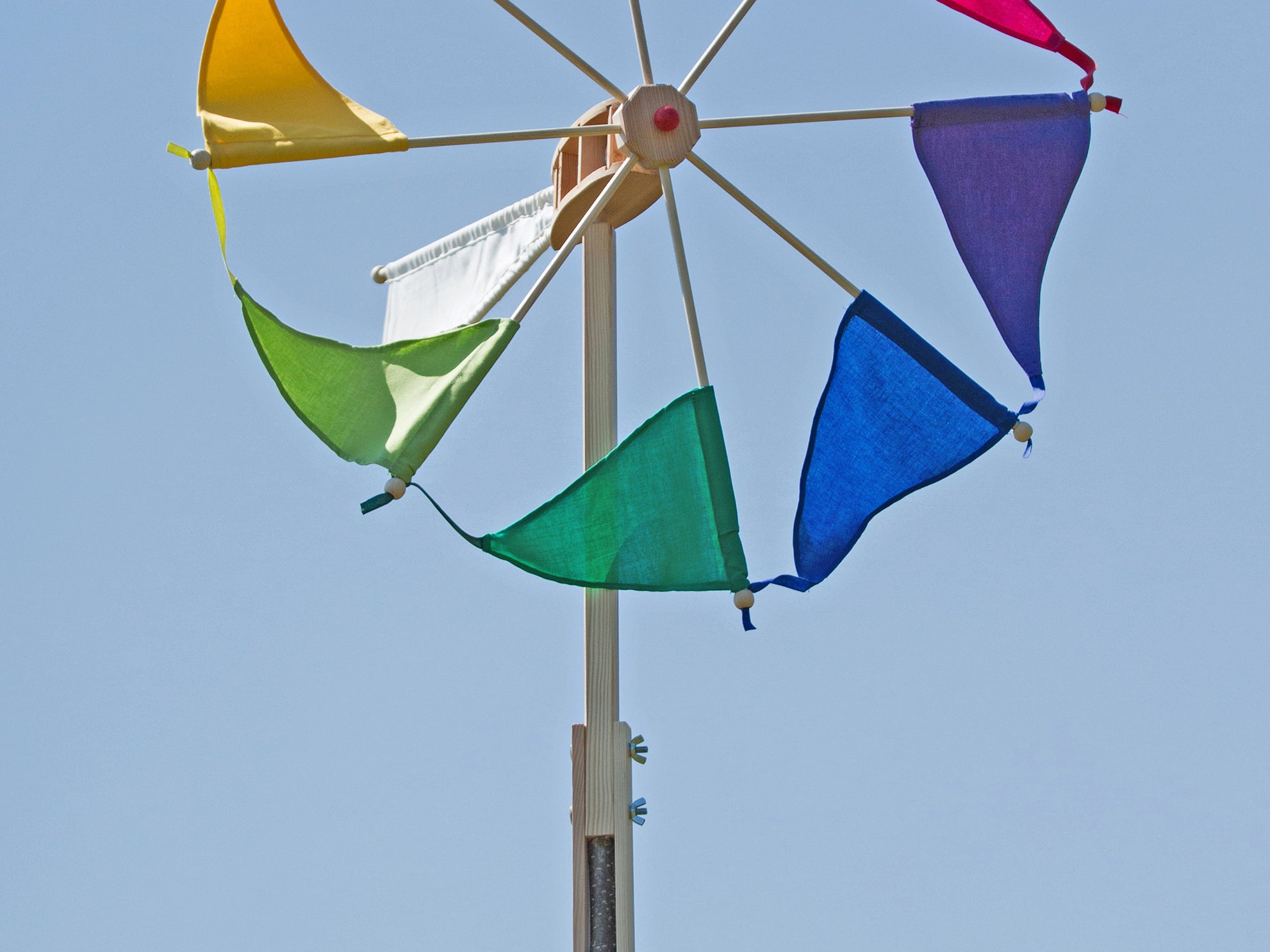 Colorful windmill with triangular flags against a clear blue sky