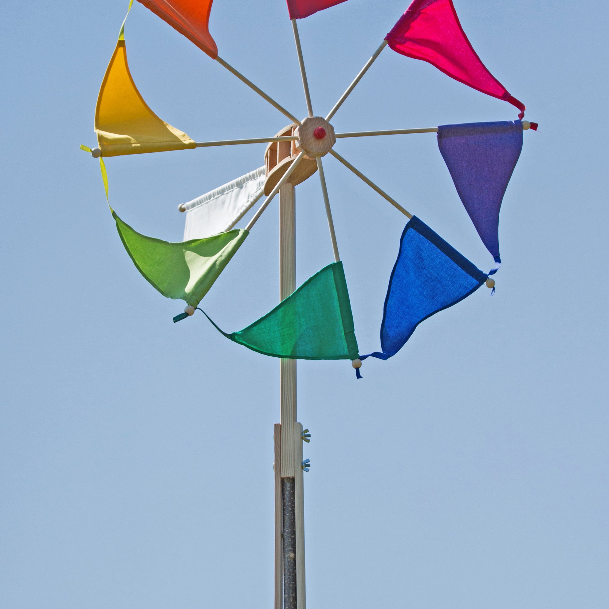 Colorful windmill with triangular flags against a clear blue sky