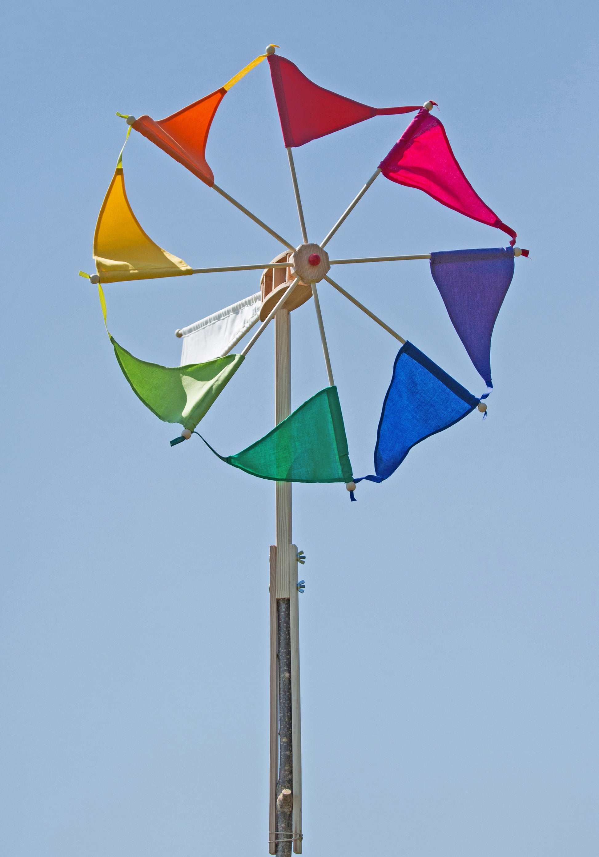 Colorful windmill with triangular flags against a clear blue sky