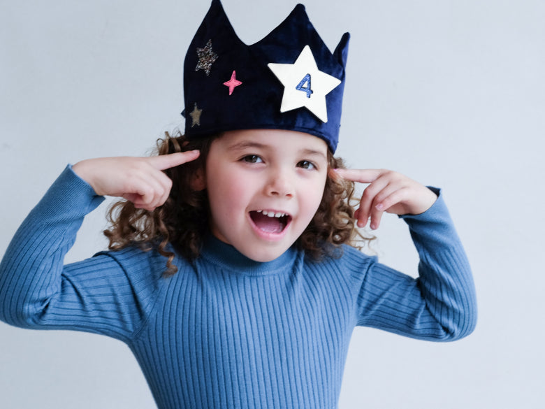 Child wearing a blue velvet crown with removable star number designs 