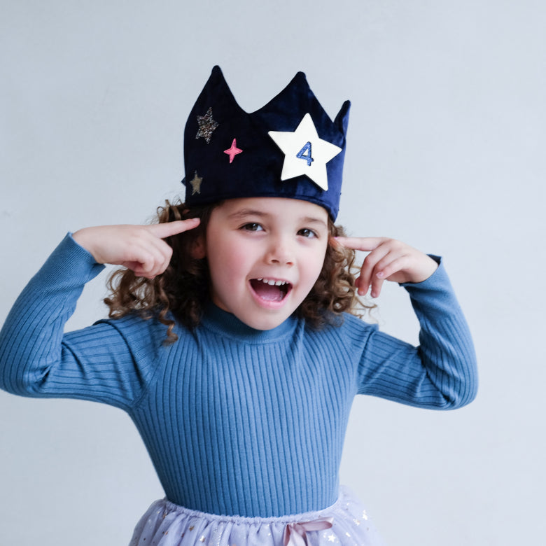 Child wearing a blue velvet crown with removable star number designs 