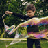 Child blowing large soap bubbles in a park setting