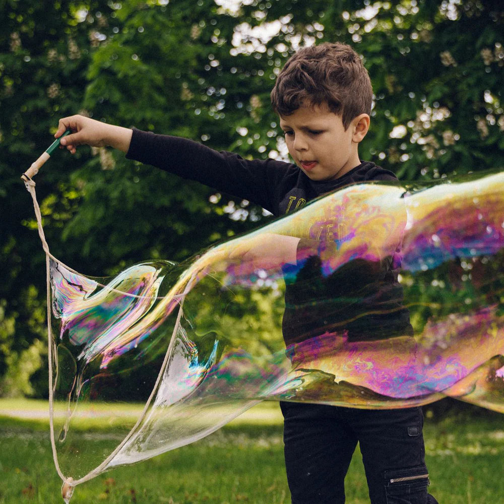 Child blowing large soap bubbles in a park setting