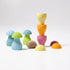 A set of pastel wooden toy mushrooms and matching caps arranged on a clean white studio background. The toys include light blue, lime green, mint green, pink, yellow, orange, and purple pieces, with one natural snail shell included.