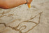 Person drawing on sand with a yellow tool