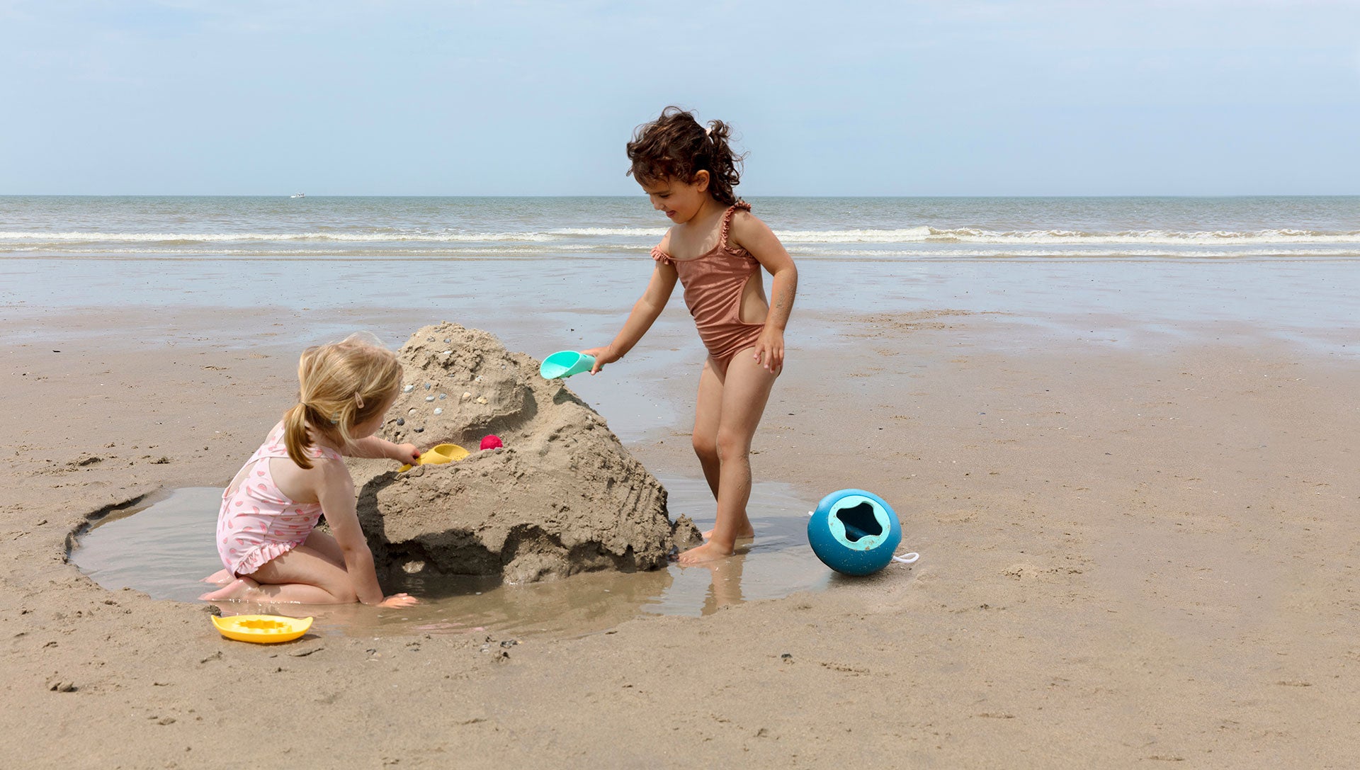 Two children playing with sand toys on a beach.