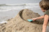 Child building a sandcastle on a beach with ocean waves in the background