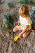 Child playing in sand with toys on a beach