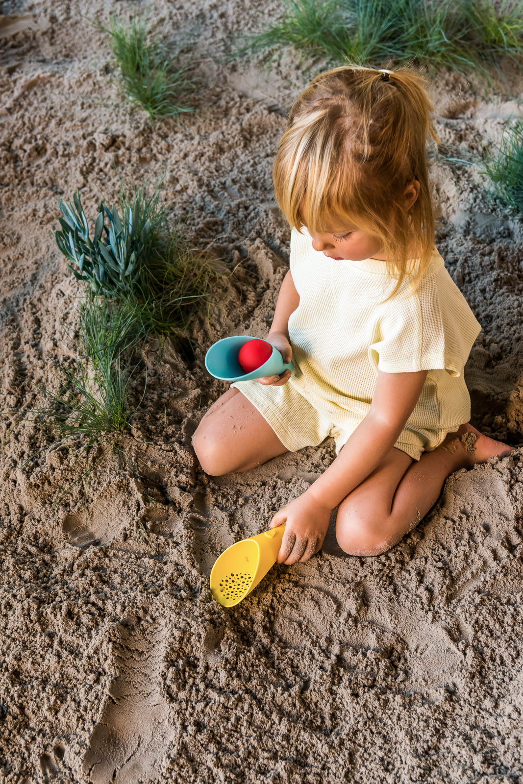 Child playing in sand with toys on a beach