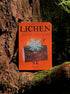 Book titled 'Lichen' by Rob Hodgson on a tree trunk in a forest setting
