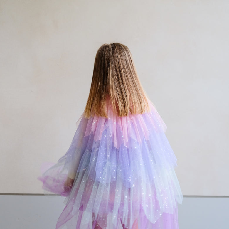 Child wearing a pastel-colored tulle dress with a star pattern against a plain background