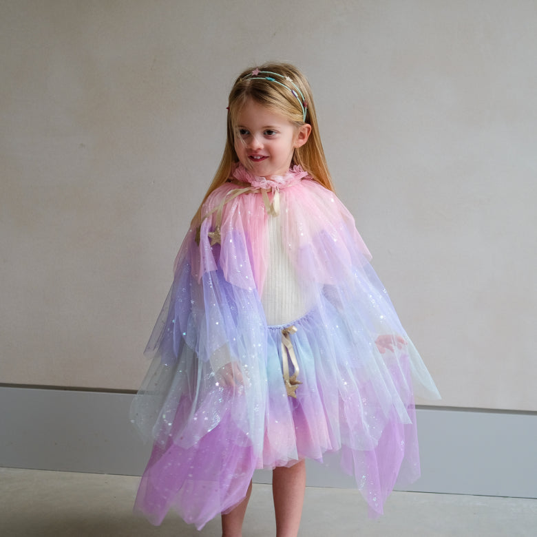 Young girl wearing a colorful fairy costume against a plain background
